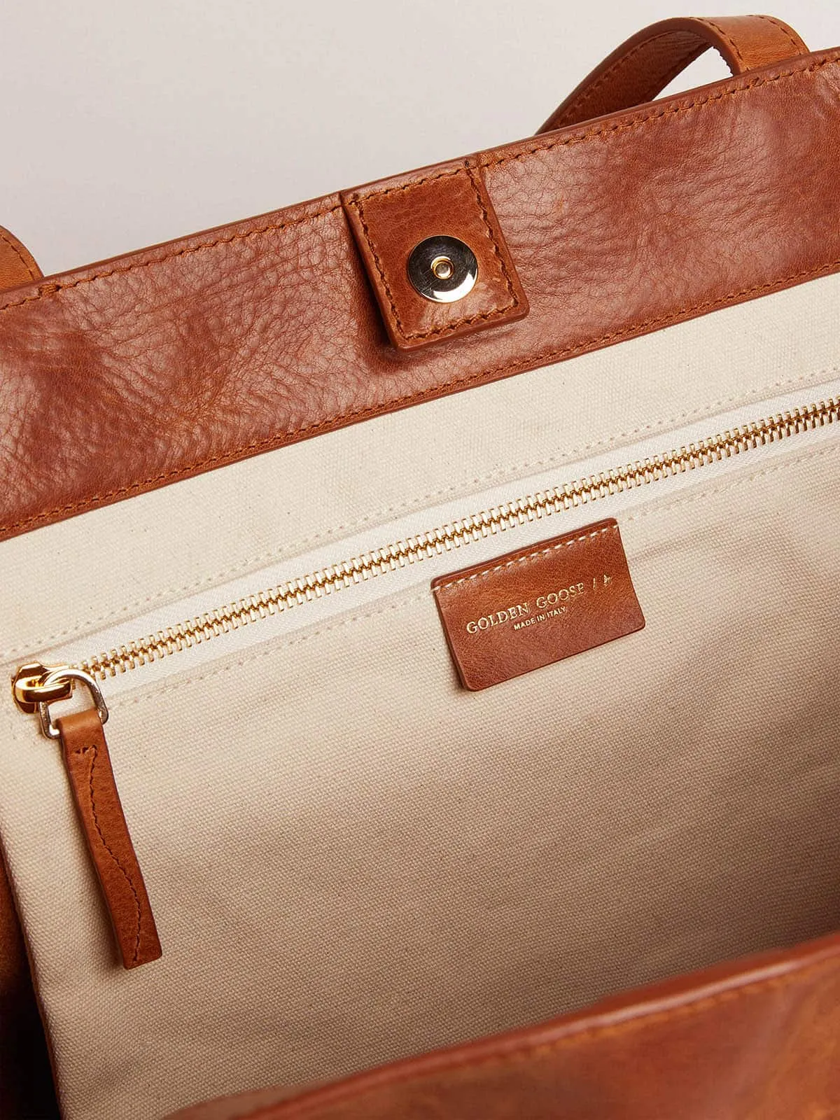 Pasadena Bag in tan-colored glossy hammered leather with gold logo on the front